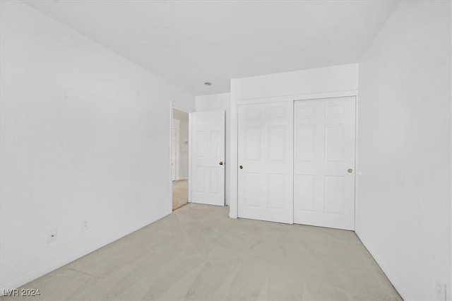 unfurnished bedroom featuring light carpet and a closet