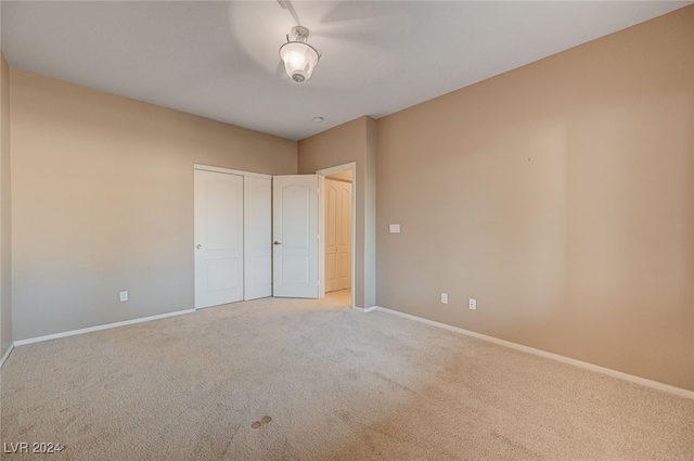 unfurnished bedroom featuring light colored carpet and a closet