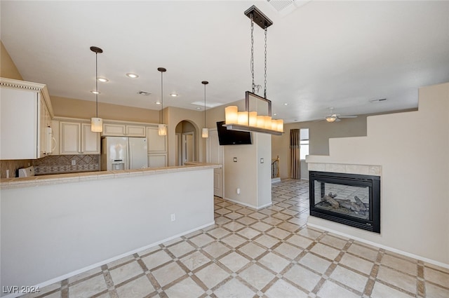 kitchen featuring decorative backsplash, pendant lighting, white appliances, and a tiled fireplace