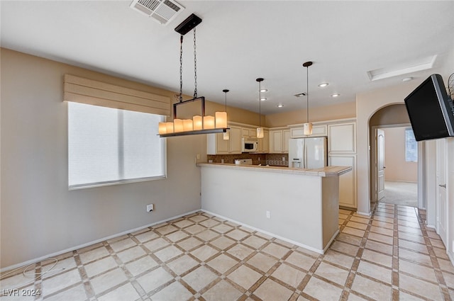 kitchen featuring backsplash, white appliances, kitchen peninsula, and hanging light fixtures