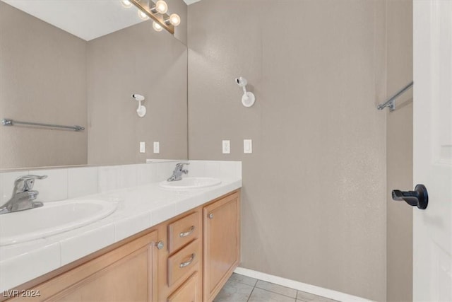 bathroom with double vanity, tile patterned flooring, baseboards, and a sink