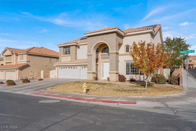 mediterranean / spanish home with a garage, a tile roof, driveway, and stucco siding