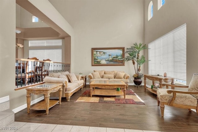 living area with a high ceiling, baseboards, and wood finish floors