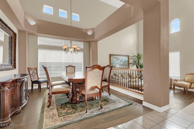 dining area with a wealth of natural light, a high ceiling, a notable chandelier, and wood finished floors