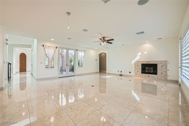 unfurnished living room with ceiling fan, a fireplace, and french doors