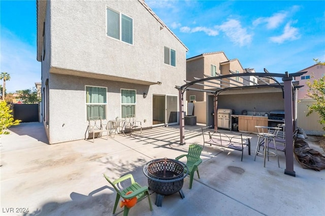 back of property with exterior kitchen, a patio area, a pergola, and an outdoor fire pit