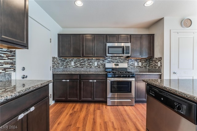 kitchen with stone counters, dark brown cabinets, light hardwood / wood-style floors, and appliances with stainless steel finishes