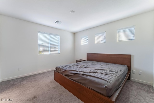 bedroom featuring light carpet and multiple windows