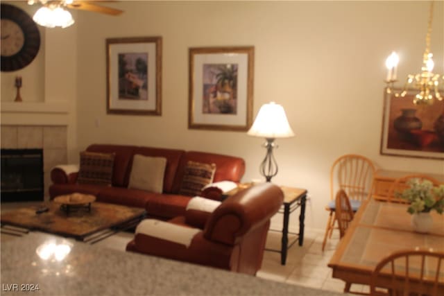 living room with a fireplace, light tile patterned floors, and ceiling fan with notable chandelier