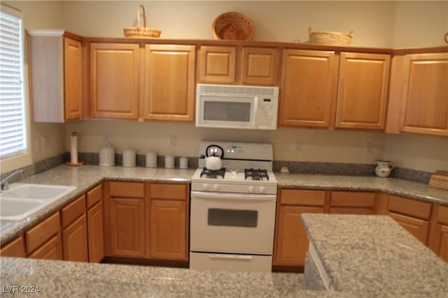 kitchen featuring light stone countertops, sink, and white appliances