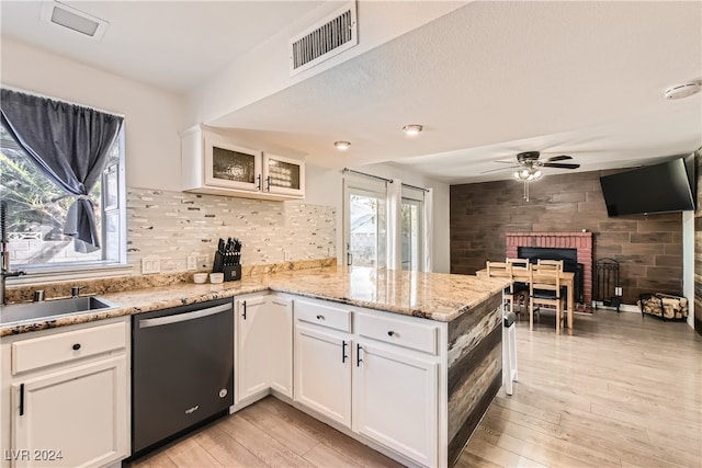 kitchen featuring light stone countertops, light wood-type flooring, stainless steel dishwasher, sink, and white cabinets