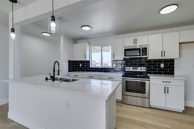 kitchen featuring appliances with stainless steel finishes, decorative light fixtures, white cabinetry, and sink