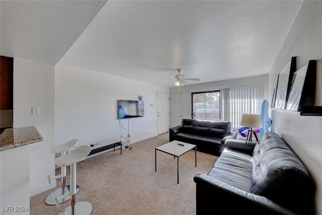 living room with ceiling fan, light colored carpet, and a textured ceiling