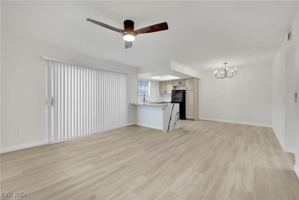 unfurnished living room featuring ceiling fan with notable chandelier, sink, and light hardwood / wood-style flooring