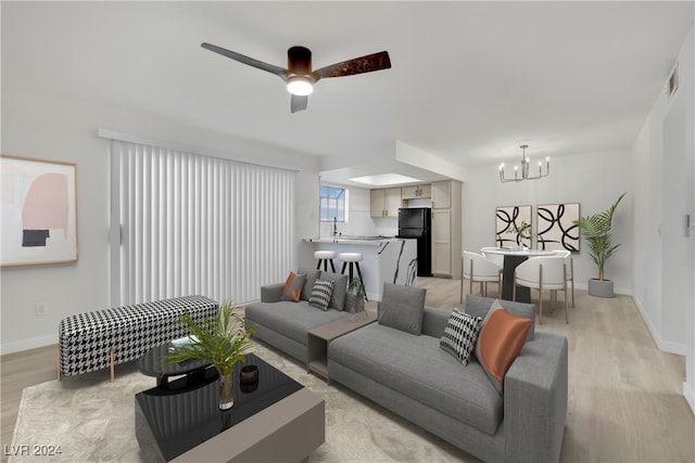 living room featuring ceiling fan with notable chandelier, light hardwood / wood-style floors, and sink