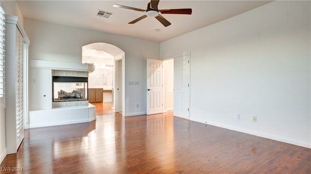 unfurnished living room with a fireplace, dark hardwood / wood-style floors, and ceiling fan