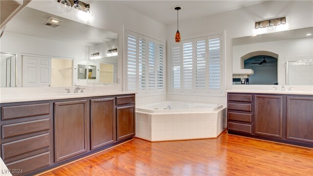 bathroom featuring tiled bath, ceiling fan, vanity, and hardwood / wood-style flooring