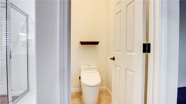 bathroom with tile patterned flooring, toilet, and a shower with shower door