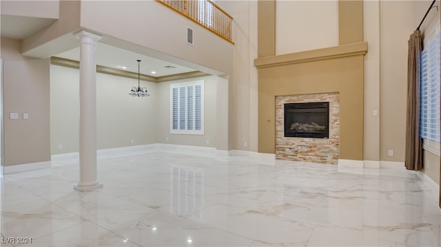 unfurnished living room with a fireplace, a high ceiling, and a notable chandelier