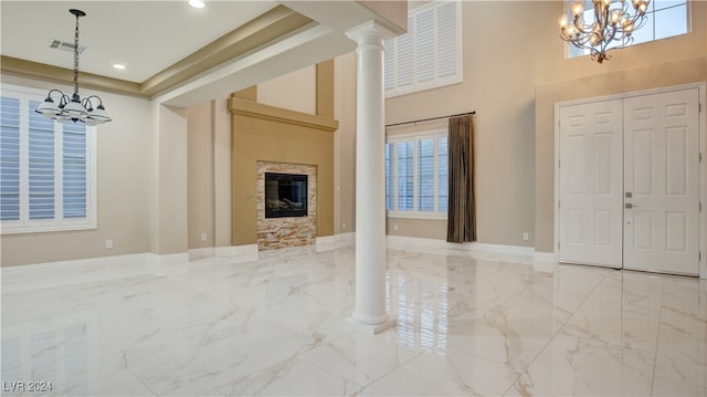 unfurnished living room with decorative columns, a fireplace, a chandelier, and a high ceiling