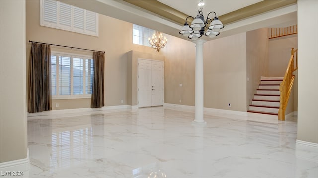 unfurnished room with plenty of natural light, ornate columns, a high ceiling, and an inviting chandelier