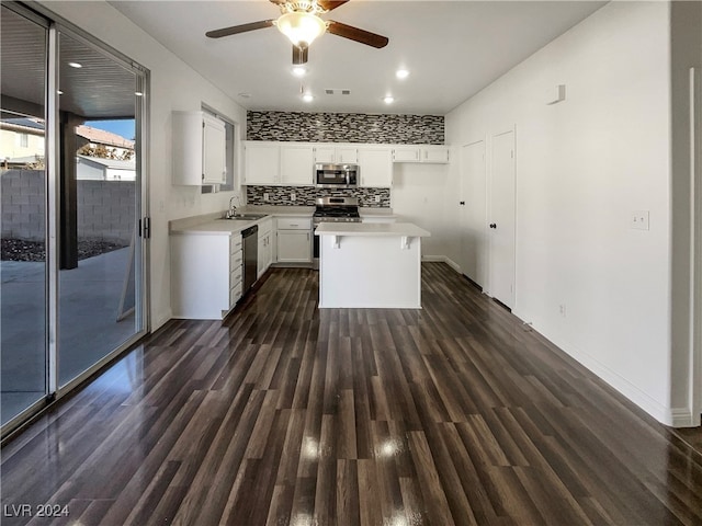 kitchen featuring tasteful backsplash, stainless steel appliances, dark wood-type flooring, a center island, and white cabinetry