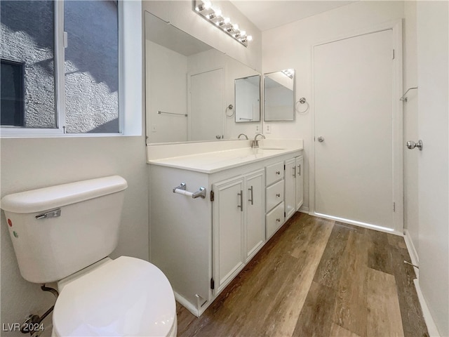 bathroom with wood-type flooring, vanity, and toilet