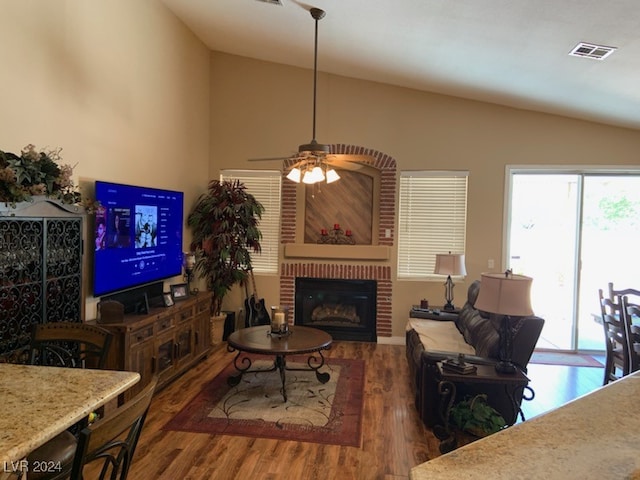 living room with a brick fireplace, dark hardwood / wood-style flooring, vaulted ceiling, and ceiling fan