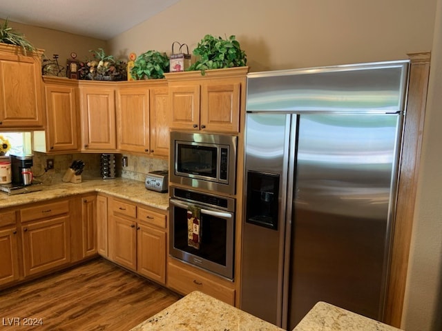 kitchen featuring built in appliances, light stone countertops, and light hardwood / wood-style floors