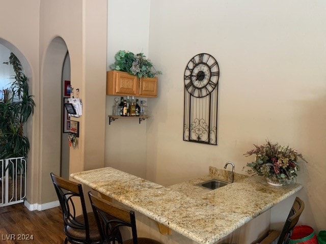 bar featuring dark hardwood / wood-style floors, light stone countertops, and sink