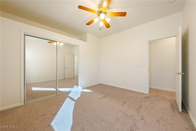 unfurnished bedroom featuring ceiling fan, a closet, and light carpet