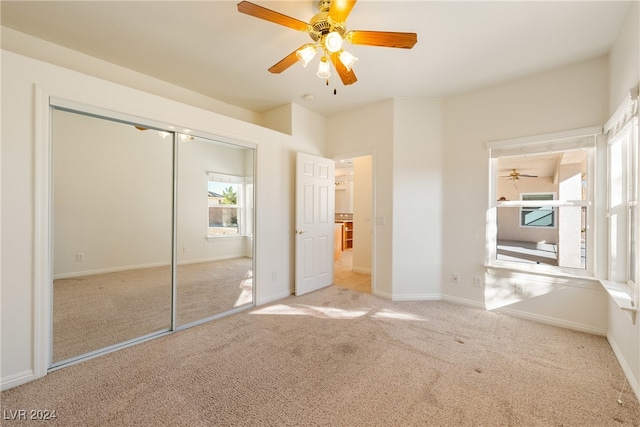 unfurnished bedroom featuring light carpet, a closet, and ceiling fan