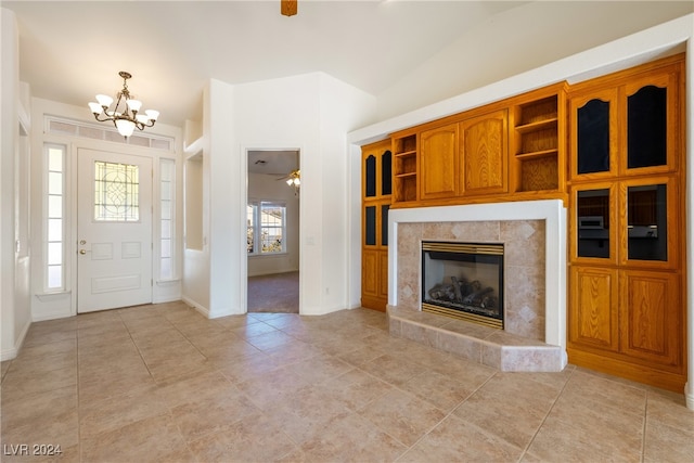 unfurnished living room with ceiling fan with notable chandelier, a healthy amount of sunlight, lofted ceiling, and a fireplace