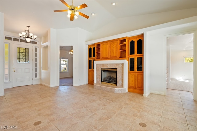 unfurnished living room with a fireplace, light tile patterned floors, ceiling fan with notable chandelier, and vaulted ceiling