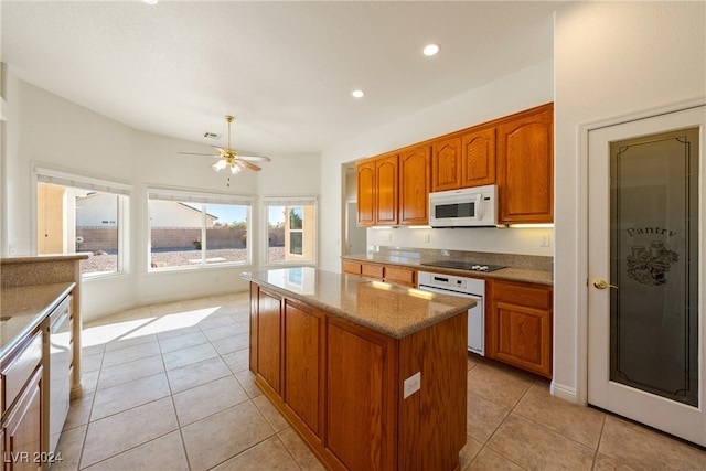 kitchen with light stone countertops, ceiling fan, light tile patterned flooring, white appliances, and a kitchen island