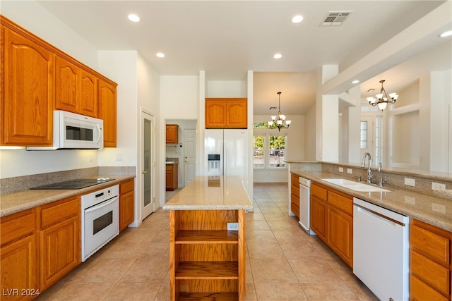 kitchen with a center island, white appliances, sink, hanging light fixtures, and a chandelier