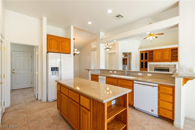 kitchen with pendant lighting, white appliances, ceiling fan with notable chandelier, sink, and vaulted ceiling