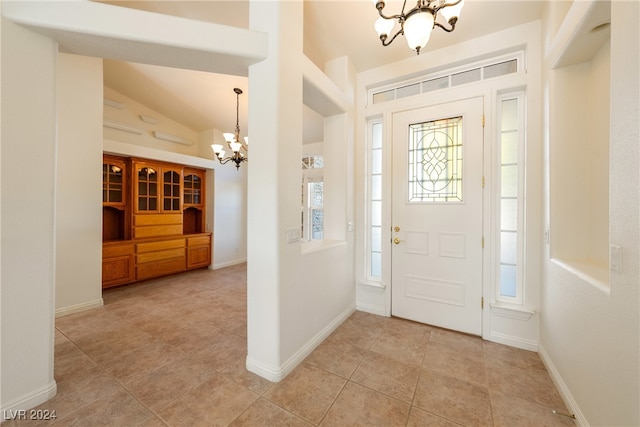 entrance foyer with light tile patterned floors, vaulted ceiling, and an inviting chandelier