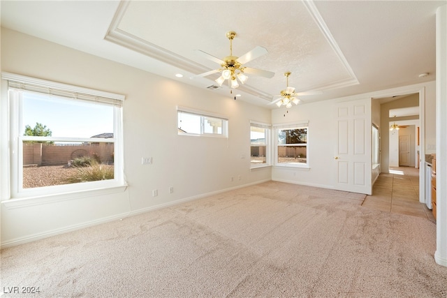 unfurnished living room with ceiling fan, light carpet, and a tray ceiling