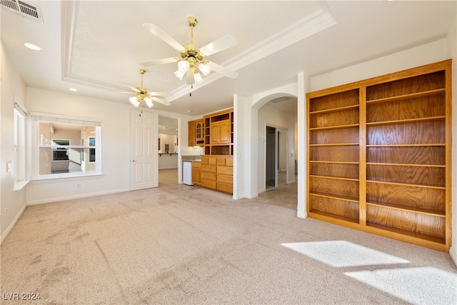 unfurnished living room with carpet floors, a raised ceiling, ceiling fan, and crown molding