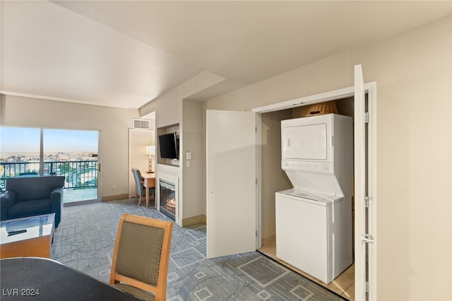 laundry area featuring stacked washer / drying machine and carpet floors