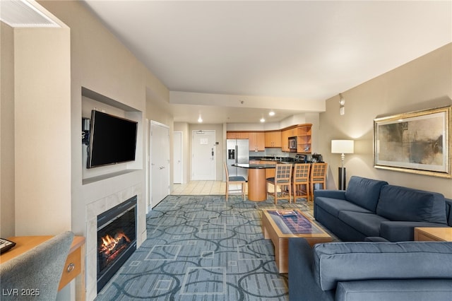 living area with recessed lighting, light colored carpet, and a fireplace