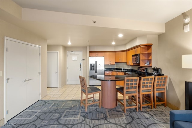 kitchen featuring recessed lighting, a peninsula, a sink, appliances with stainless steel finishes, and dark countertops