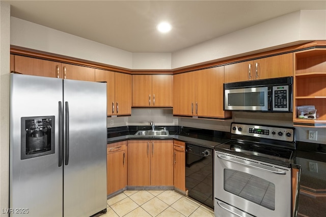 kitchen with light tile patterned flooring, a sink, appliances with stainless steel finishes, brown cabinetry, and dark countertops