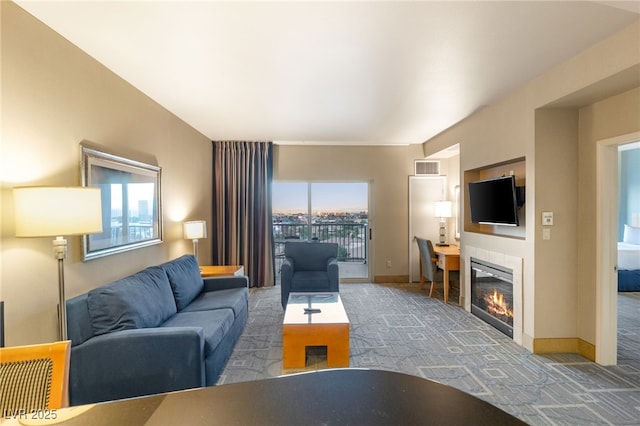 living room with carpet floors, a glass covered fireplace, visible vents, and baseboards