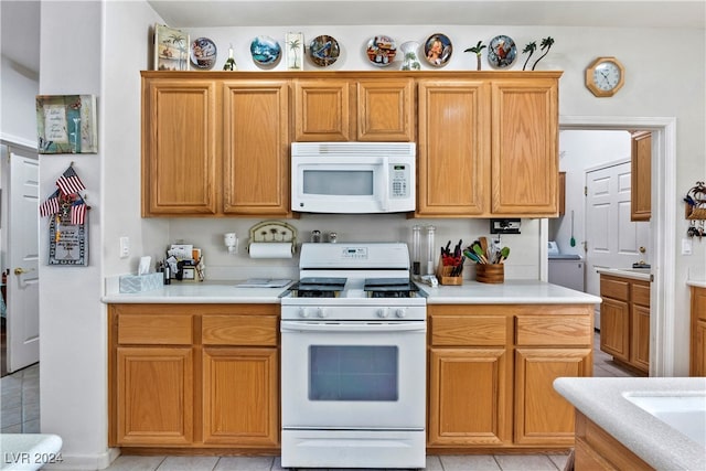 kitchen with light tile patterned floors, white appliances, and washer / clothes dryer