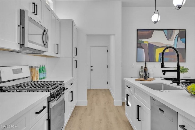 kitchen with appliances with stainless steel finishes, light hardwood / wood-style floors, white cabinetry, and sink