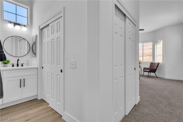 hall featuring light colored carpet and sink