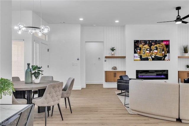 dining space featuring ceiling fan with notable chandelier and light wood-type flooring