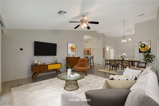 living room featuring light tile patterned floors, ceiling fan with notable chandelier, and vaulted ceiling